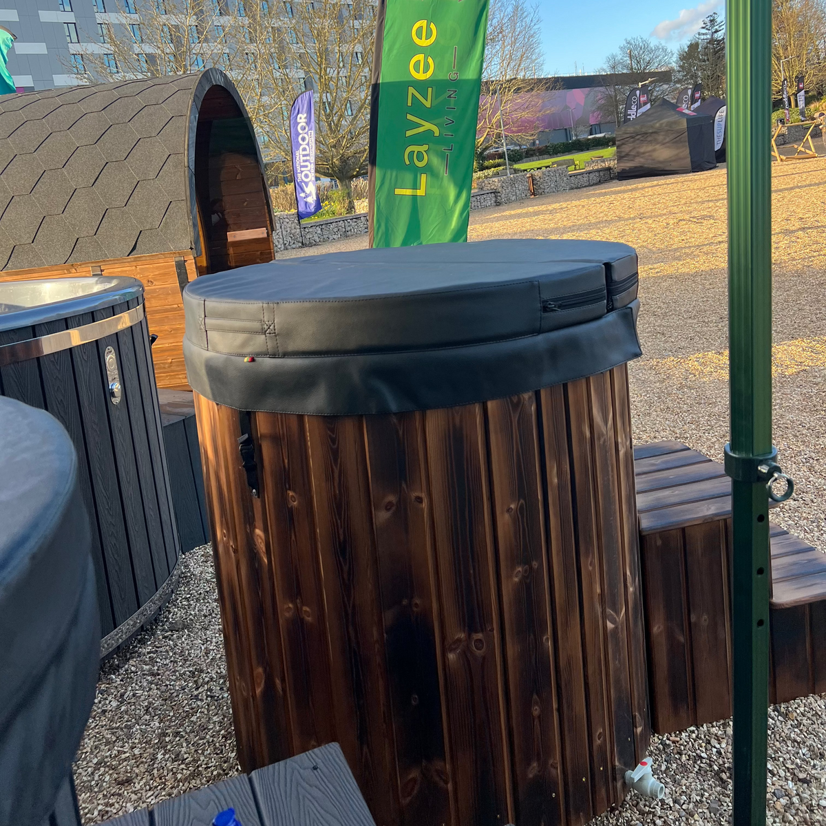 Wooden barrel with a green 'Layzee' flag in an outdoor setting