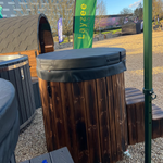 Wooden barrel with a green 'Layzee' flag in an outdoor setting